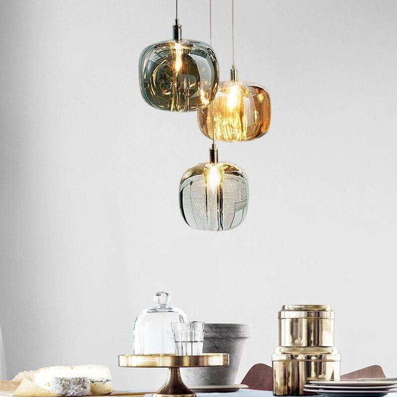 Three Clérachic mini bubble glass pendant lights clustered at staggered drops above a dining table laid with cheese and brass tins