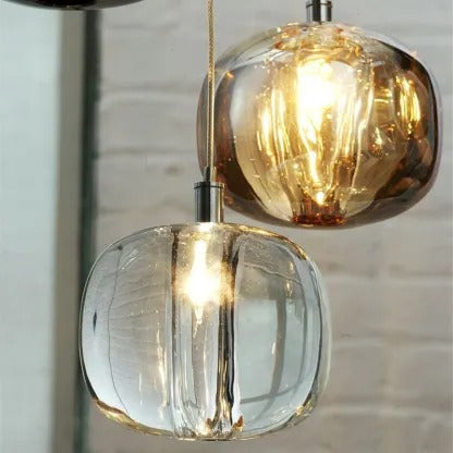 Close view of amber and clear Clérachic mini bubble glass pendant lights lit against a whitewashed brick wall
