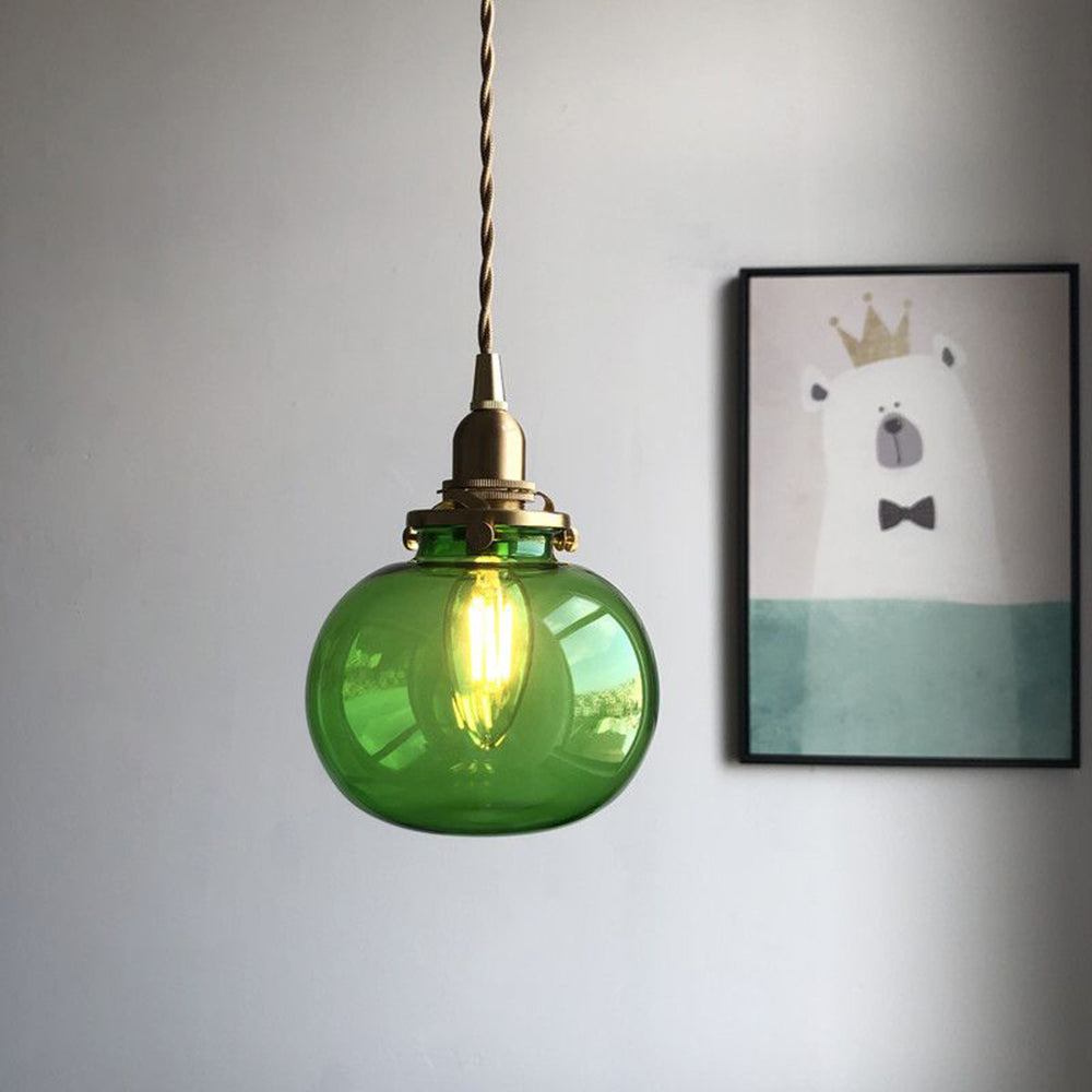 Green Clérachic Mini Glass Pendant Light, a smooth flattened oval lit to bright emerald against a plain grey wall.