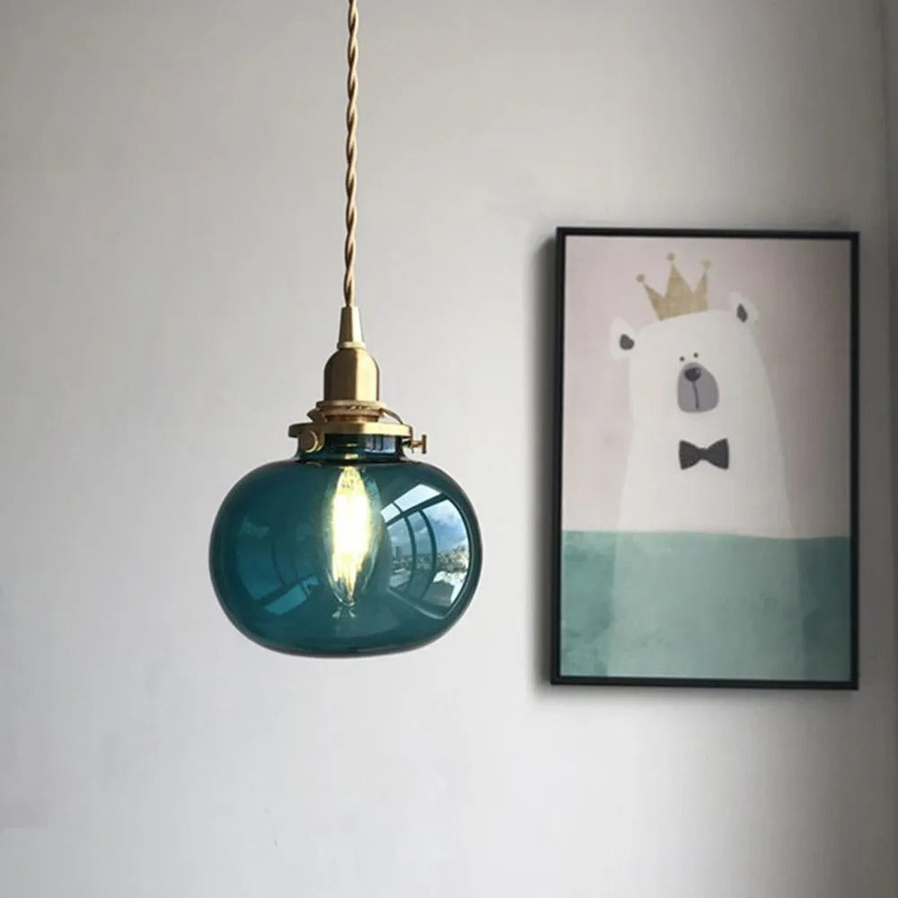 Blackish Green Clérachic Mini Glass Pendant Light lit on a twisted brass flex, reading petrol blue in low room light.