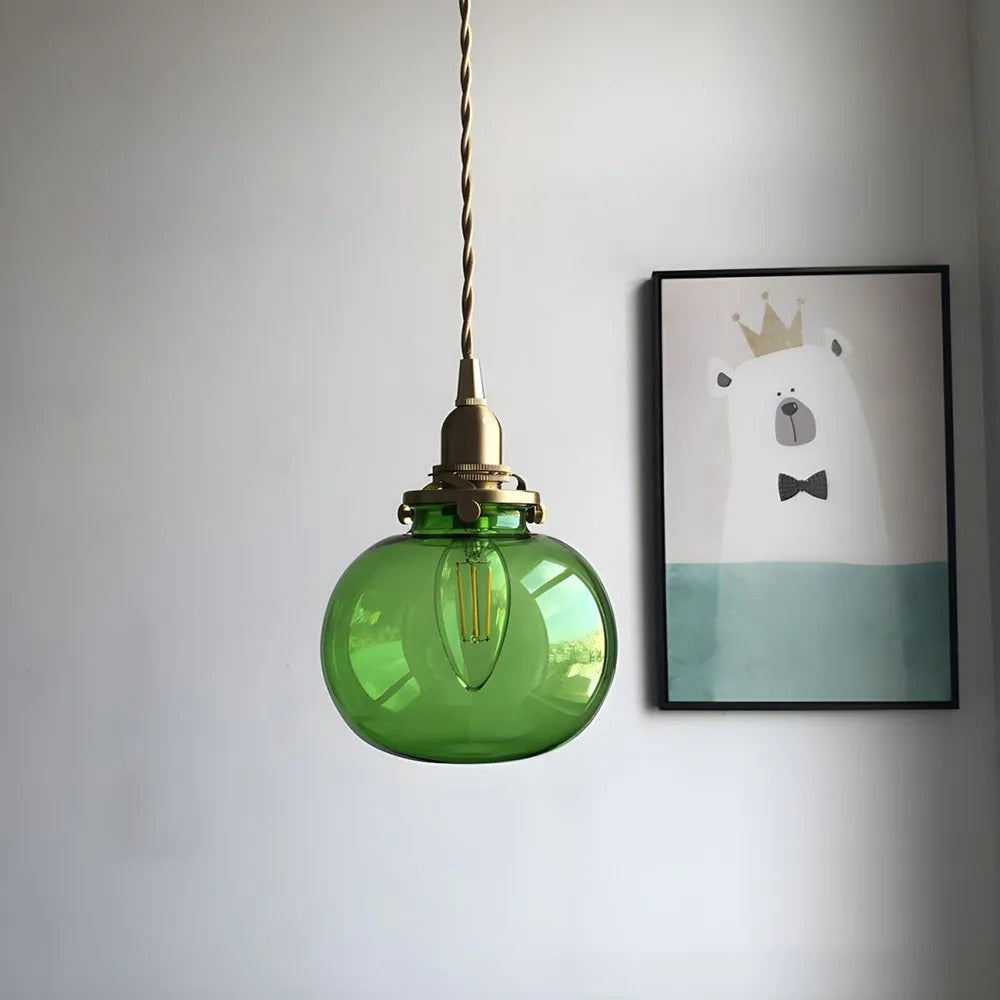 Clérachic Mini Glass Pendant Light in green seen from below, the candelabra filament bulb visible through the oval shade.