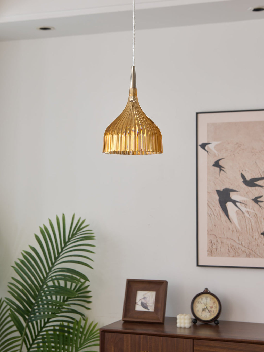 Clérachic fluted pendant light in amber, its deep gold ribs shown in daylight against the pale living-room wall above the console.