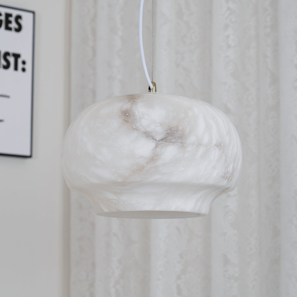 Clérachic alabaster pendant unlit beside a lace curtain, natural stone reading soft cream.