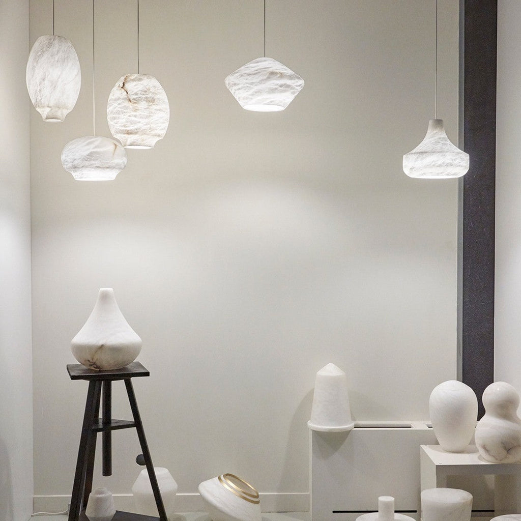 A group of Clérachic alabaster pendants hung at varied heights above a pale showroom display.