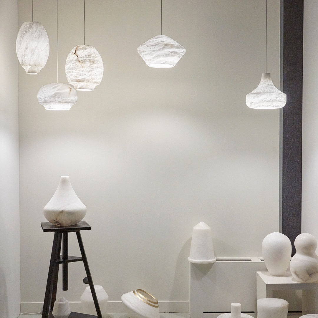 A group of Clérachic alabaster pendants hung at varied heights above a pale showroom display.