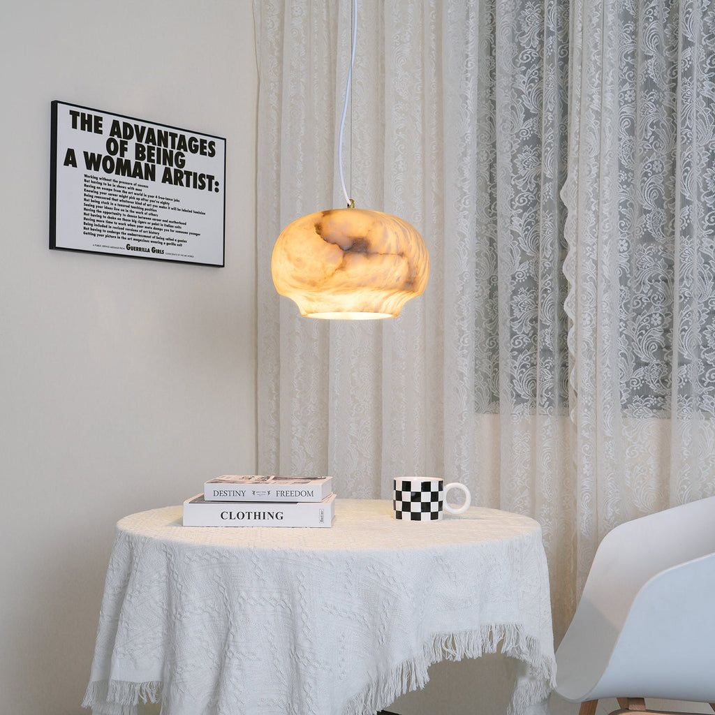 Clérachic alabaster pendant lit above a round table beside a framed print and lace curtain.