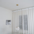 The Clérachic alabaster pendant hung in a bright white room against a sheer lace curtain.