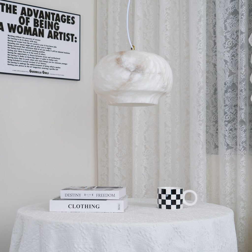 Closer view of the Clérachic alabaster pendant lit above the same round cloth-covered table.
