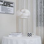 Closer view of the Clérachic alabaster pendant lit above the same round cloth-covered table.