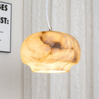 Macro of the Clérachic alabaster shade lit from within, amber tones flooding the stone grain.