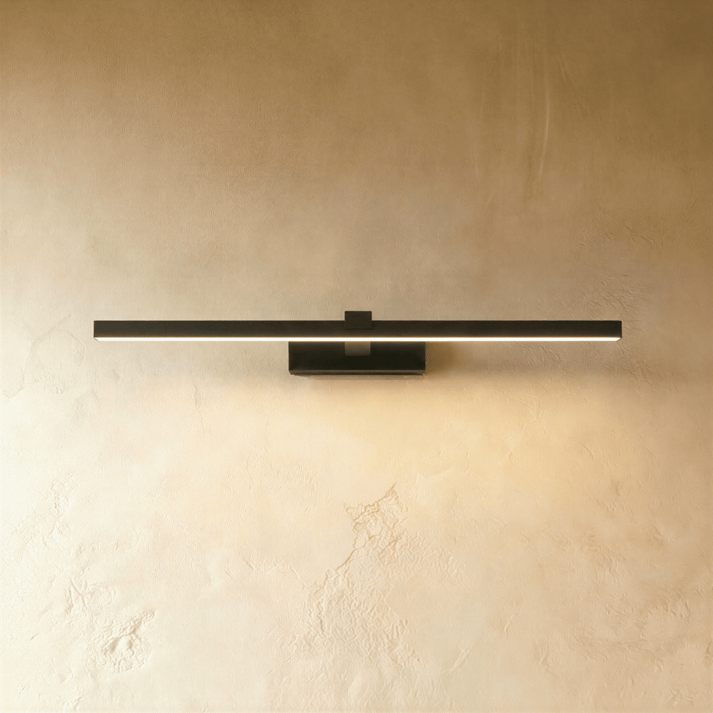 Clérachic slim black linear wall light in a longer length, lit along the diffuser on a warm textured limewash wall.