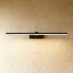 Clérachic slim black linear wall light in its longest length, lit along the diffuser on a textured limewash wall.