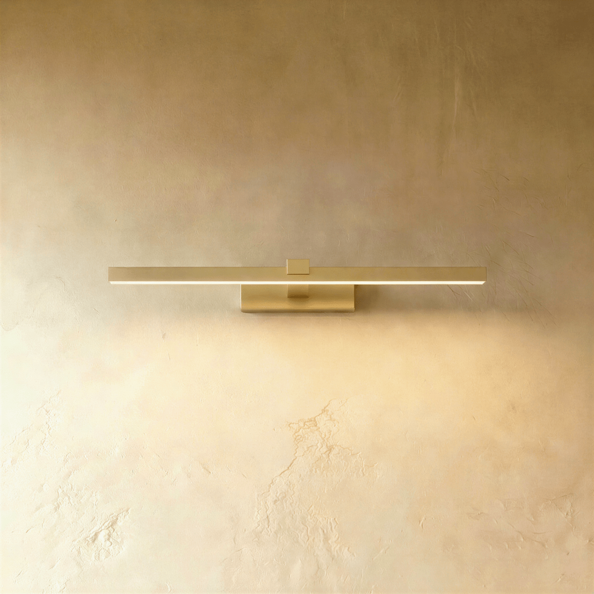 Clérachic slim brushed gold linear wall light, 39.5 cm, glowing along its diffuser on a textured limewash wall.