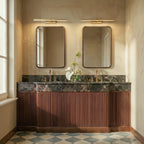 Clérachic gold linear wall lights above two framed mirrors over a marble double vanity with fluted wooden cabinets.