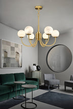 Clérachic globe chandelier lit in a grey living room above a green velvet sofa and round mirror.