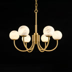 Clérachic alabaster globe chandelier lit on black, warm light held inside each stone sphere.
