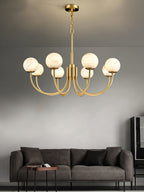 The Clérachic globe chandelier hung above a dark grey sofa on a pale plaster wall.