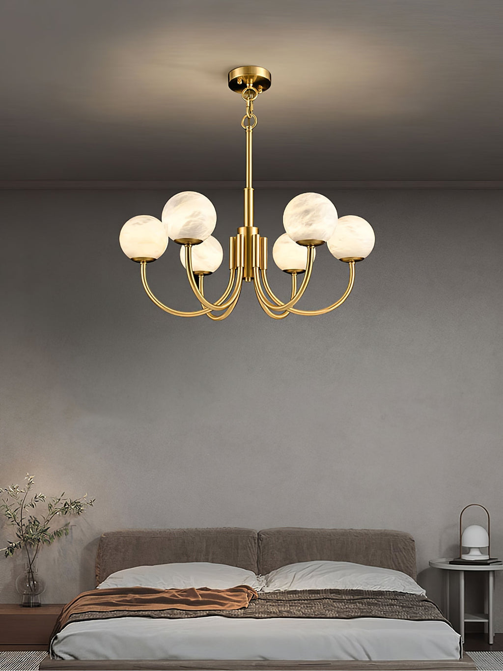 Clérachic globe chandelier lit in a bedroom, warm globes against a soft grey wall above the bed.