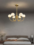 Clérachic globe chandelier lit in a bedroom, warm globes against a soft grey wall above the bed.