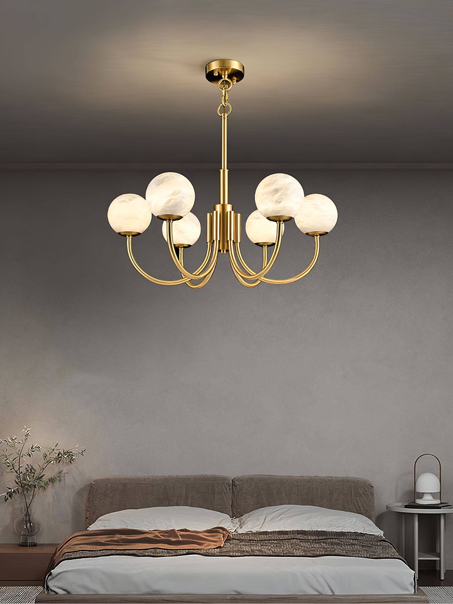 Clérachic globe chandelier lit in a bedroom, warm globes against a soft grey wall above the bed.