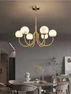 Clérachic globe chandelier above a dining table in an arched room with upholstered chairs.