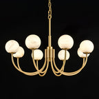 The Clérachic globe chandelier angled on black, showing the sweep of each brass arm.
