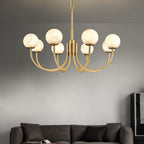 Clérachic globe chandelier lit above a dark sofa, warm globes against a smooth grey wall.