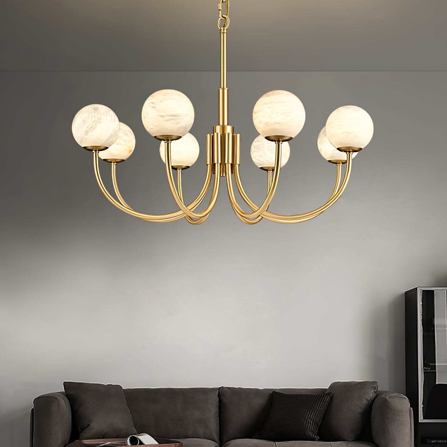 Clérachic globe chandelier lit above a dark sofa, warm globes against a smooth grey wall.