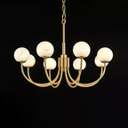 Clérachic globe chandelier lit on black, each alabaster sphere reading warm against the dark.