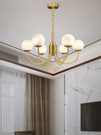 Clérachic globe chandelier in a living room with marble panelling and full-length curtains.