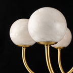 Macro of three Clérachic alabaster globes on black, the natural stone grain clearly visible.