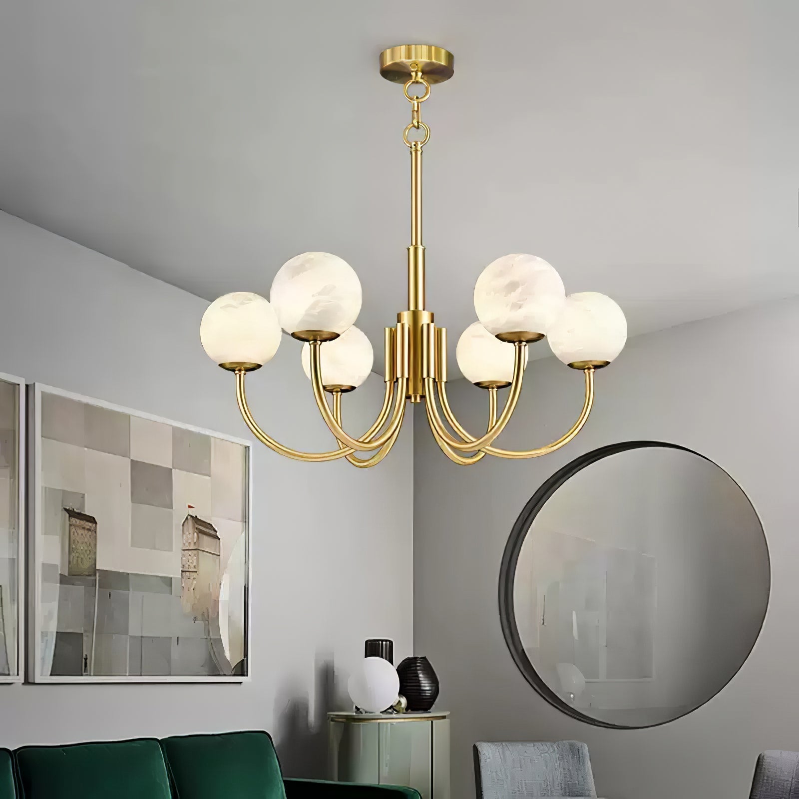 The Clérachic globe chandelier above a green sofa and circular mirror in a grey-toned room.