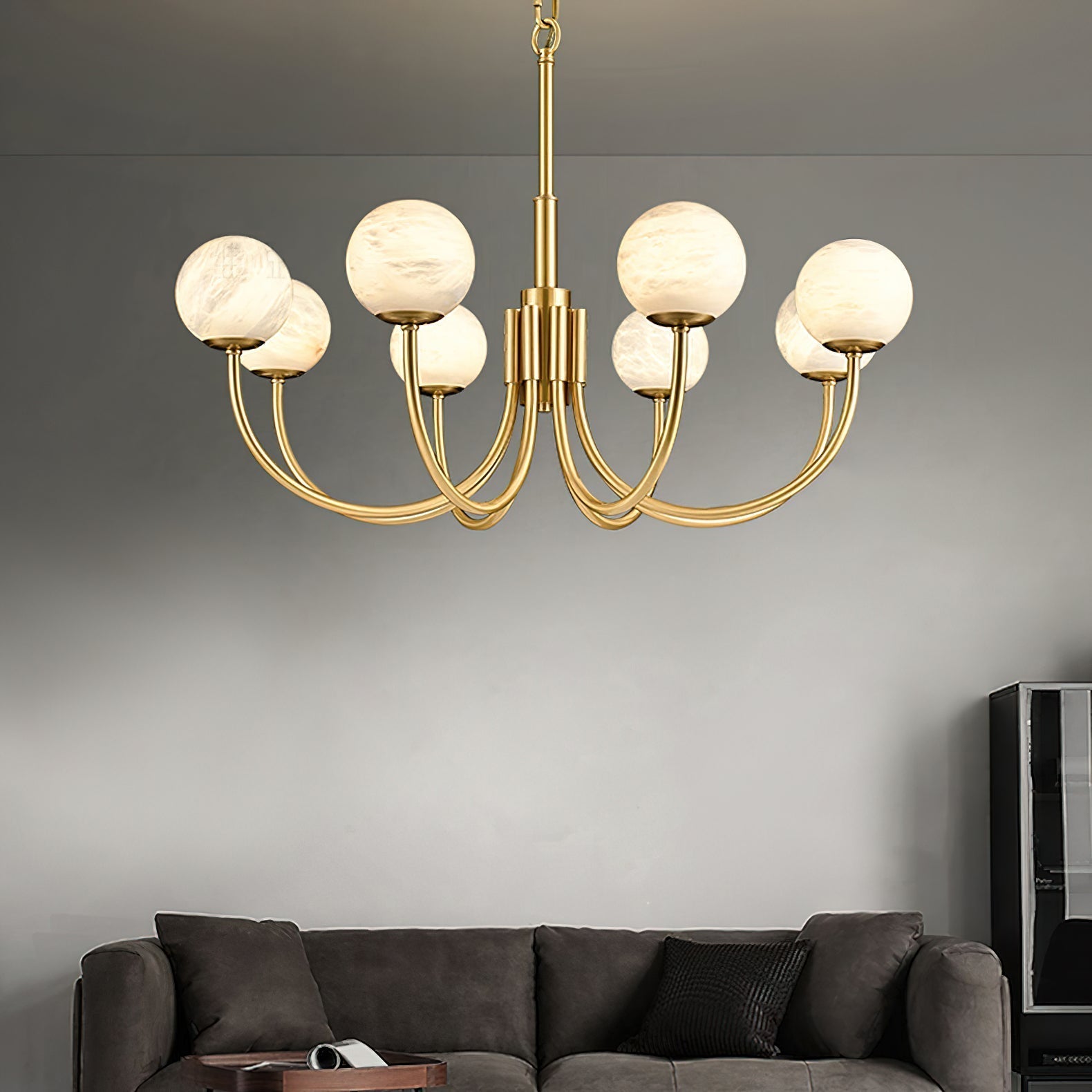 The Clérachic globe chandelier lit on grey above a dark sofa and low timber table.