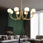 Clérachic globe chandelier hung against deep green panelling above a pale sectional sofa.