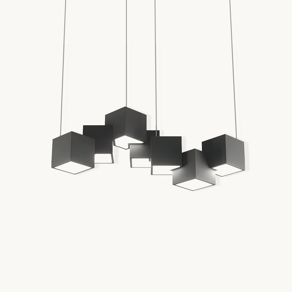 A Clérachic chandelier of black cube-shaped lights at different angles, hung on thin wires against a plain off-white backdrop.