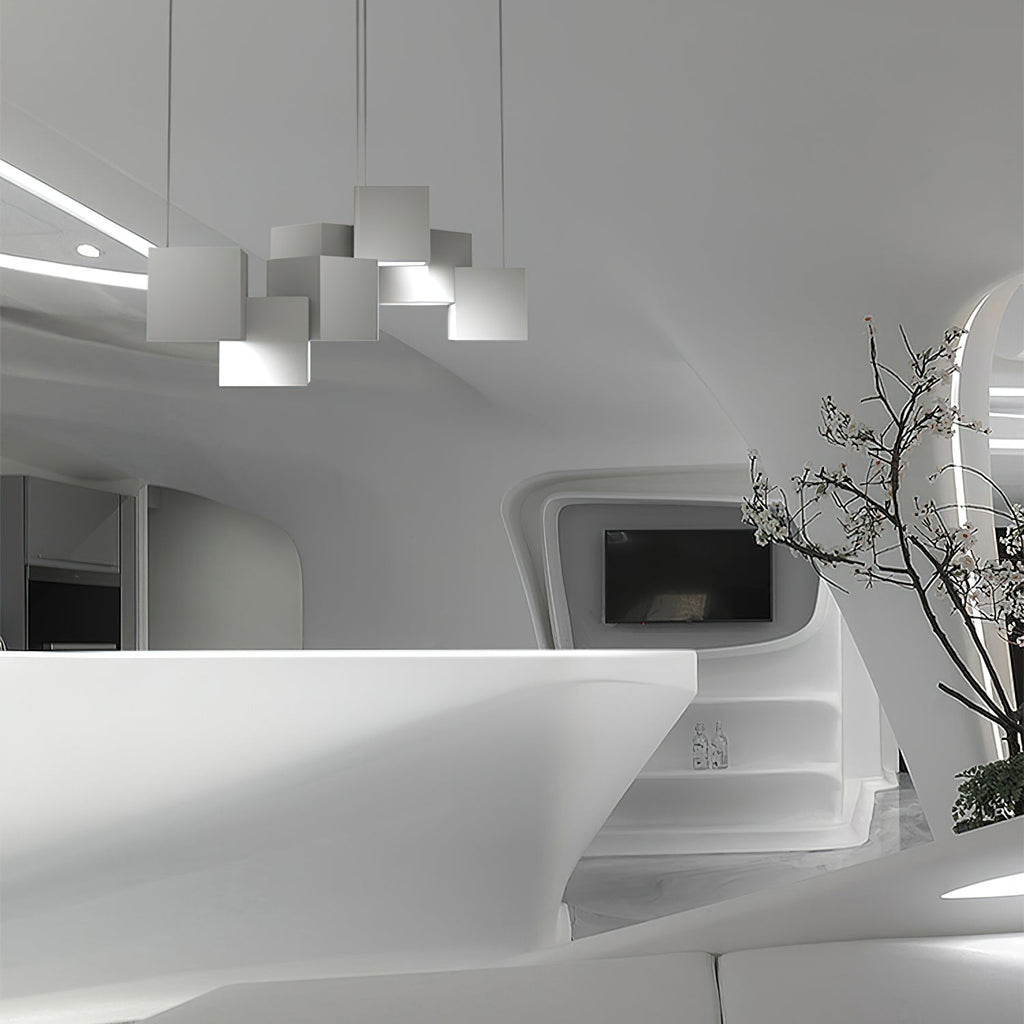 A Clérachic chandelier of white cubes seen from a distance in a curved white interior, with a branch in a vase to the right.