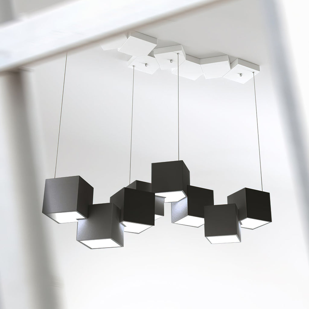 Looking up at a Clérachic chandelier of black cubes on four wires, with a white tiled canopy of cubes on the ceiling above.