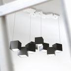 Looking up at a Clérachic chandelier of black cubes on four wires, with a white tiled canopy of cubes on the ceiling above.
