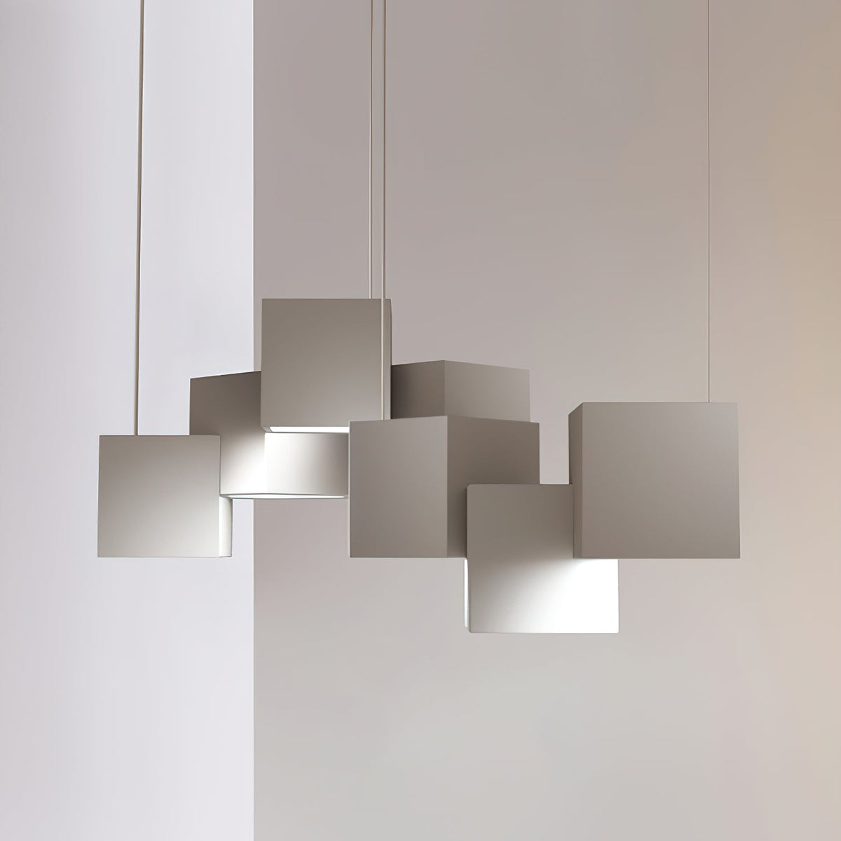 Close view of a white Clérachic cube chandelier against a pale wall, the cubes stacked at offset angles with light below.