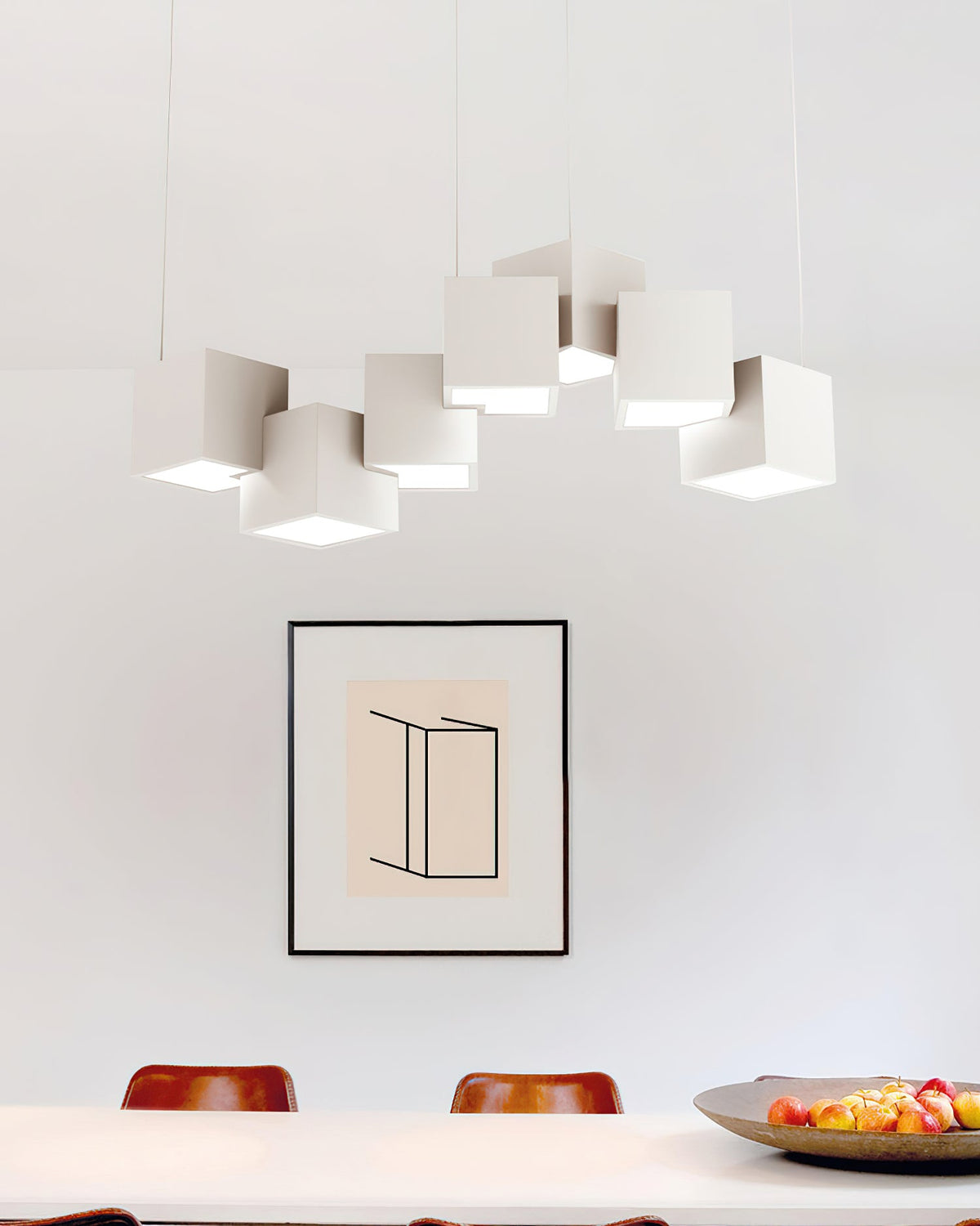 White Clérachic cube chandelier hung above a white dining table with a framed print and a bowl of fruit.
