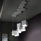 Clérachic white cube chandelier in a dark room, with a canopy of white cubes on the ceiling and a framed print on the wall.