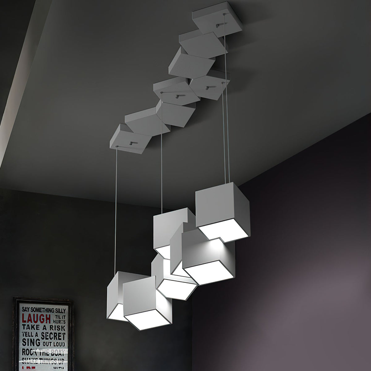 Clérachic white cube chandelier in a dark room, with a canopy of white cubes on the ceiling and a framed print on the wall.