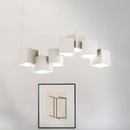 A Clérachic chandelier of white cubes in a row above a black-framed abstract print on a pale wall.