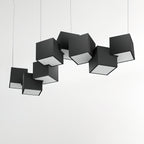A Clérachic chandelier of black cubes over a pale wall, the tilted cubes showing their white lit undersides.
