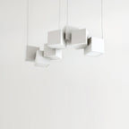 Clérachic chandelier of white cubes against a pale wall, hung at different heights and angles on four fine wires.