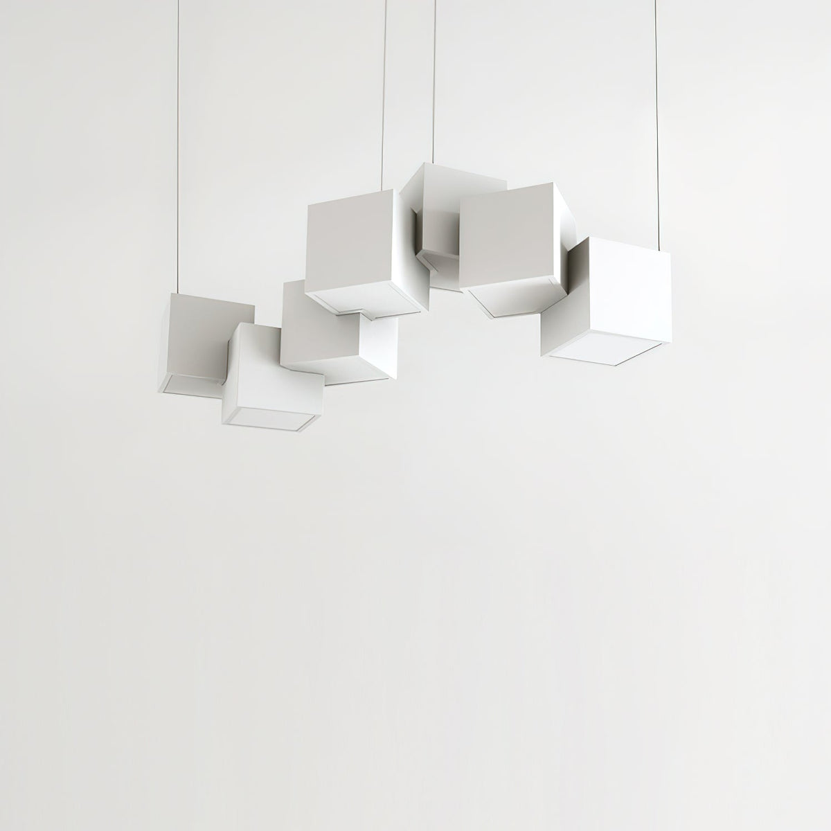 Clérachic chandelier of white cubes against a pale wall, hung at different heights and angles on four fine wires.