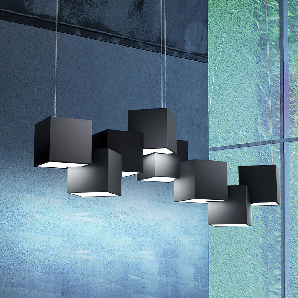 Black Clérachic cube chandelier in front of a blue-green glass and concrete wall, with light glowing from beneath each cube.