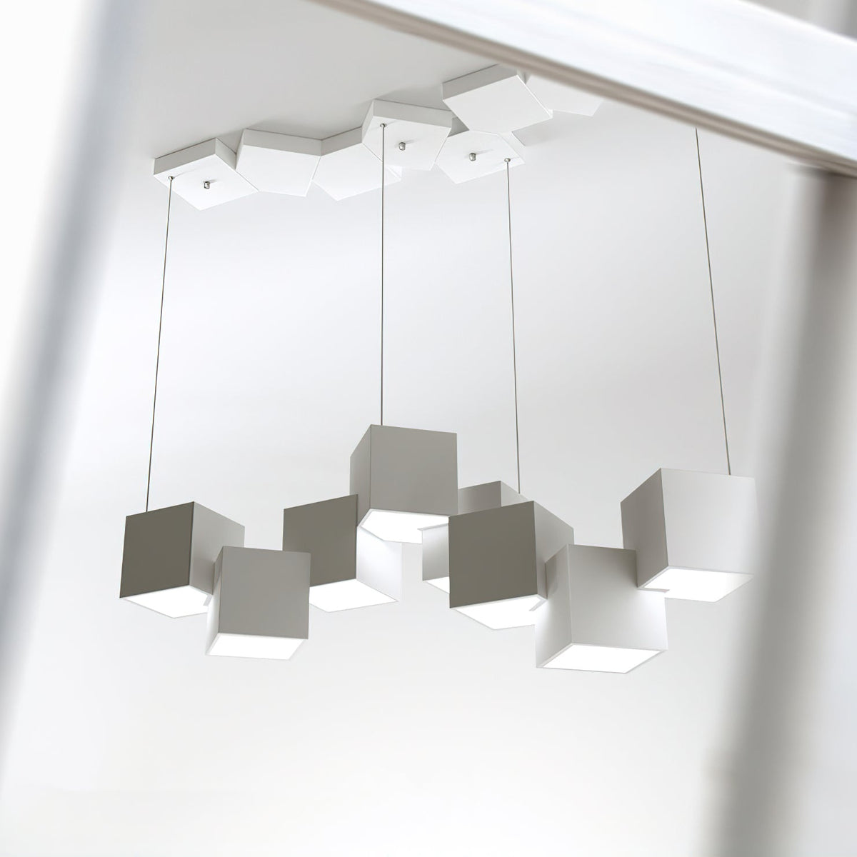 A Clérachic white and grey cube chandelier seen from below, with its cubes tilted and a canopy of cubes above.