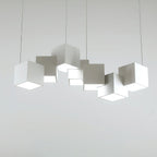 A Clérachic white cube chandelier on a light grey backdrop, the cubes at different tilts with bright undersides.