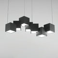 A Clérachic black cube chandelier on a light grey backdrop, shown straight on with the white undersides glowing.